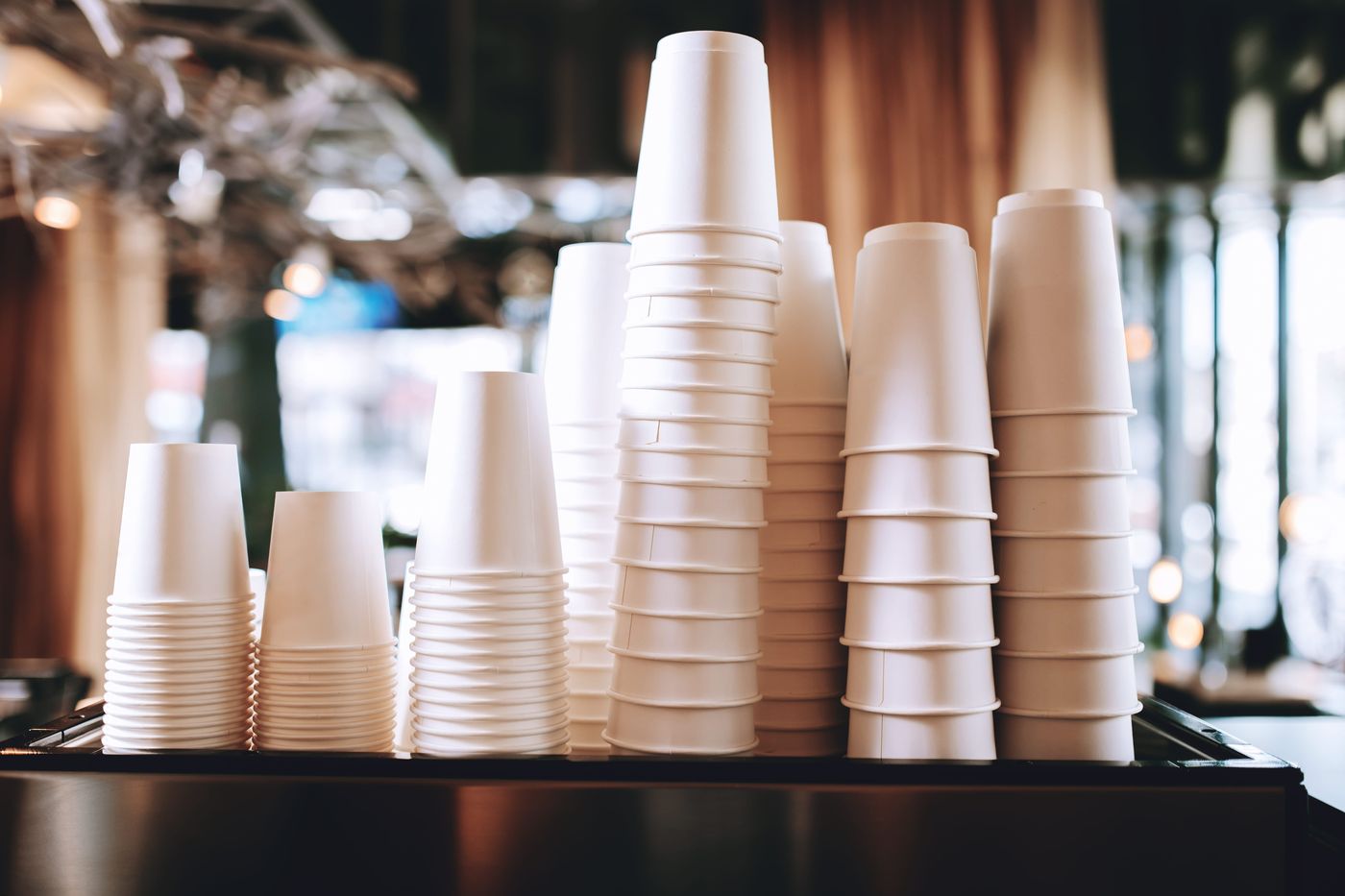 Stacks of white paper coffee cups on a café counter
