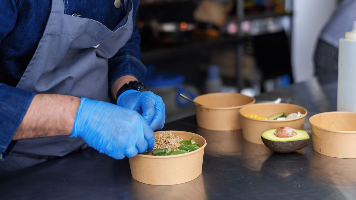 Cook filling kraft paper bowls with quinoa salad