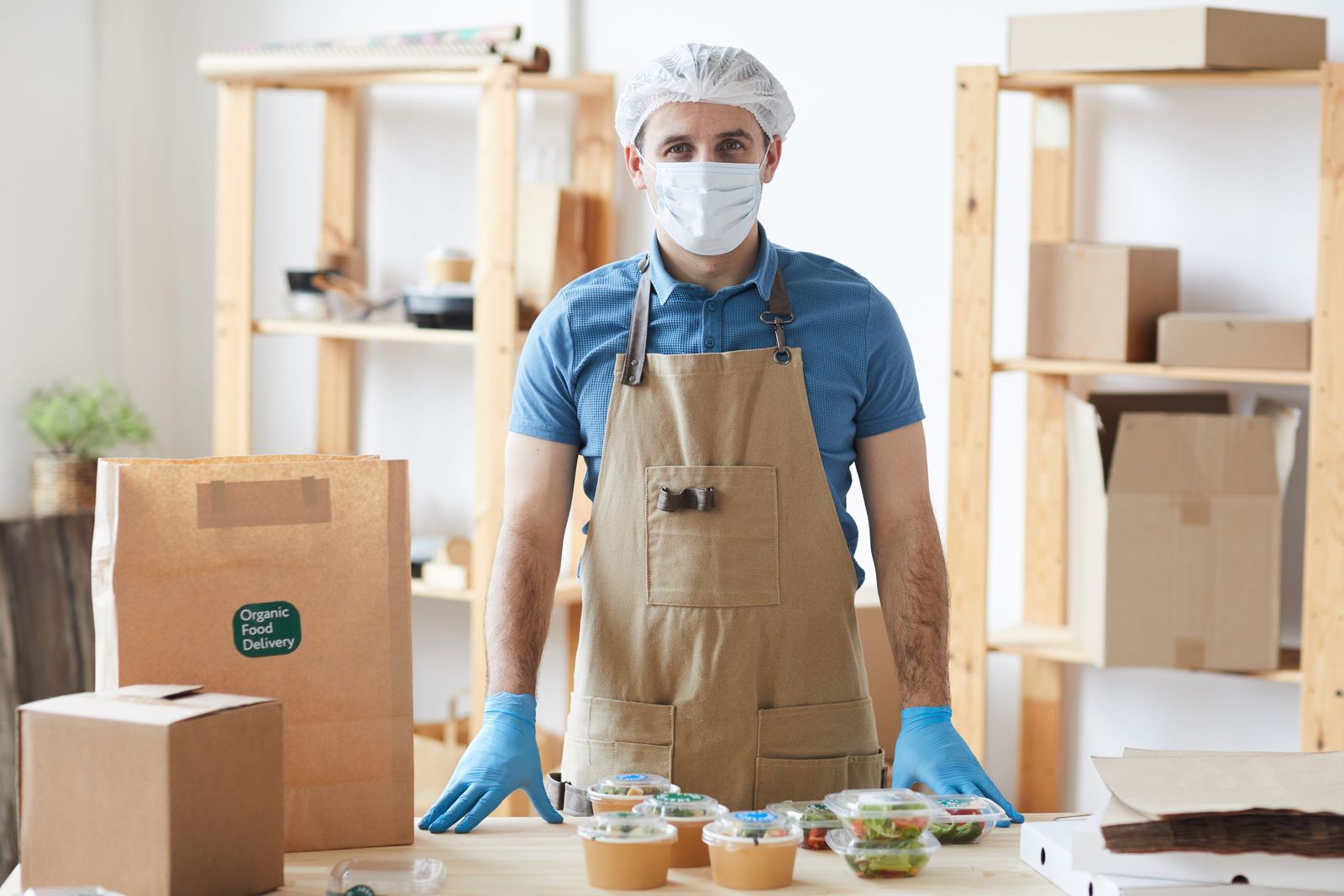 Food worker with gloves and hairnet preparing orders for delivery