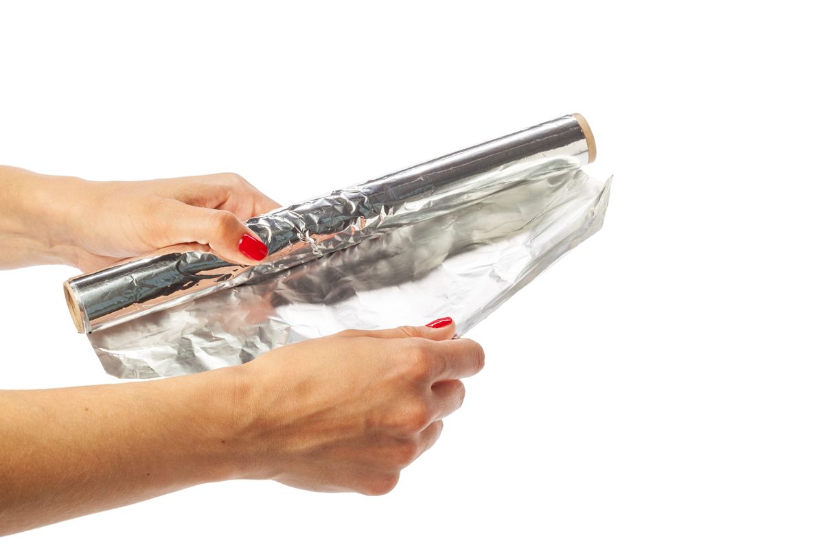 Hands unrolling aluminum foil