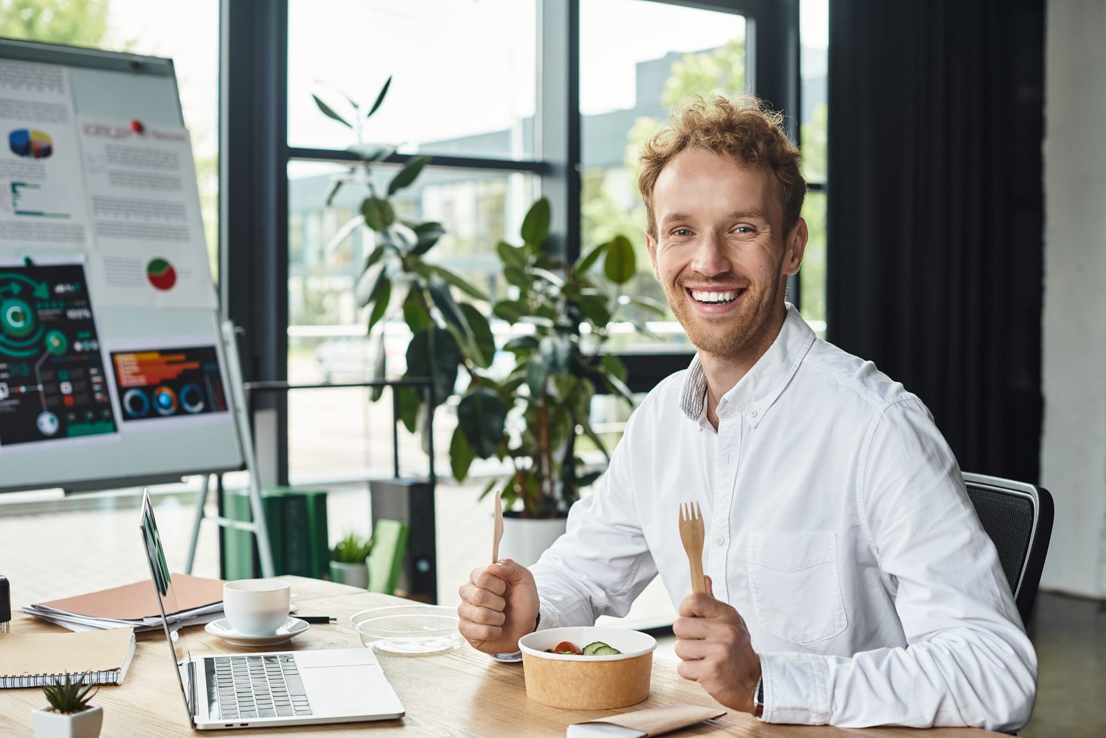 Smiling professional eating lunch from a kraft bowl at the office